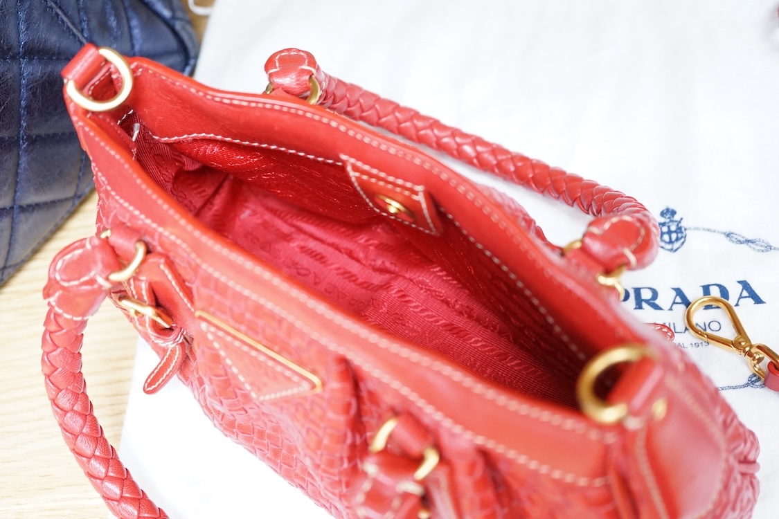 A Prada red braided leather handbag with shoulder strap, authenticity card and dust cover, 25cm wide, Provenance: Purchased by the vendor in Selfridges